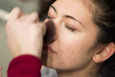 Danika Elvine, senior, gets her face painted by Pauline Moraveck, junior, as the rest of Drama prepares for the final dress rehearsal.