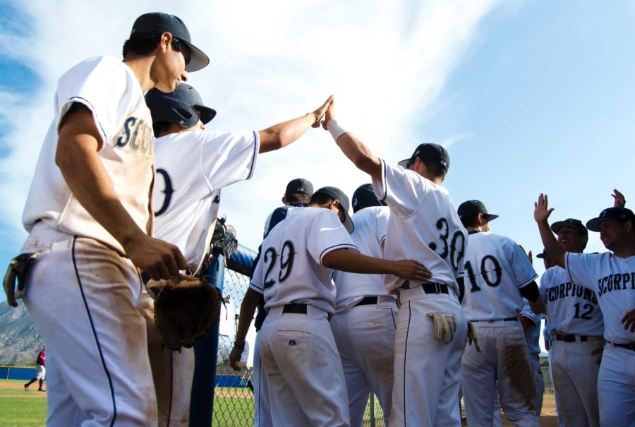 The+Baseball+team+high-fives+each+other+after+a+successful+run+at+a+Varsity+game.