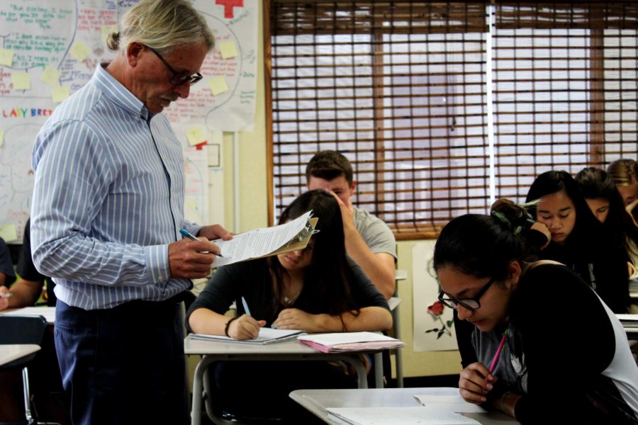Mr. Kevin Buddhu reviews his English 3 class' homework assignments.