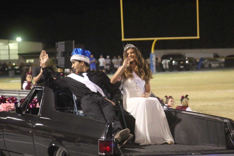 Ramtein Foghi and Sophia Cortina, junior homecoming royalty, waving to the crowd as they drive down the Cam High track during the Homecoming Game Halftime Show.