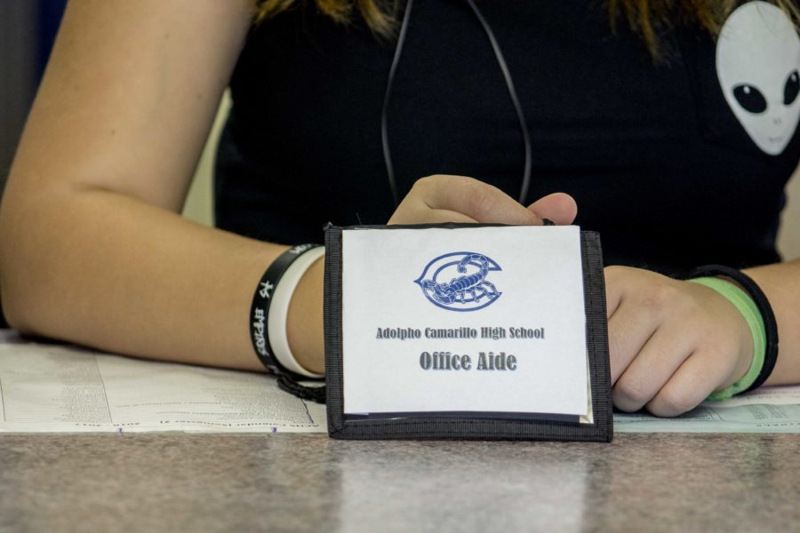 Office aide students wear a pass as they send out passes to classes around the school.