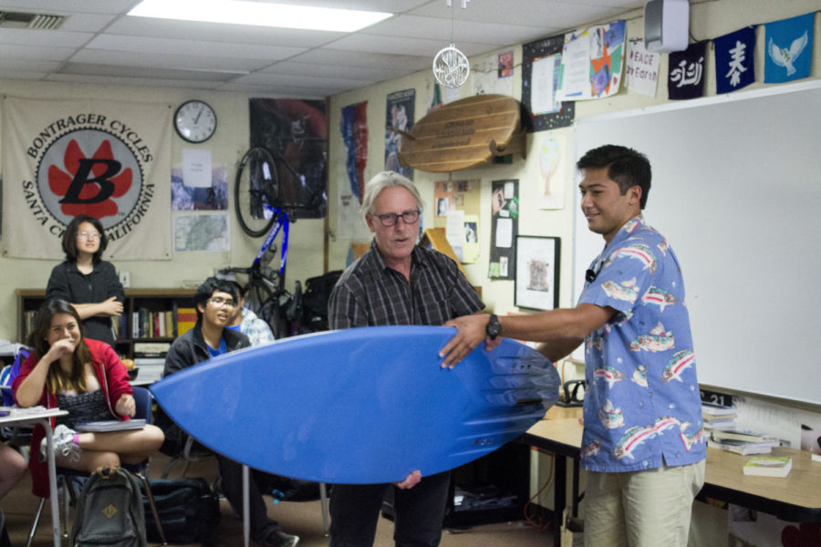 Senior Tyler Tsuji hands Mr. Kevin Buddhu his customized surfboard presented by his AP Literature classes as a goodbye gift before he leaves to Spain.